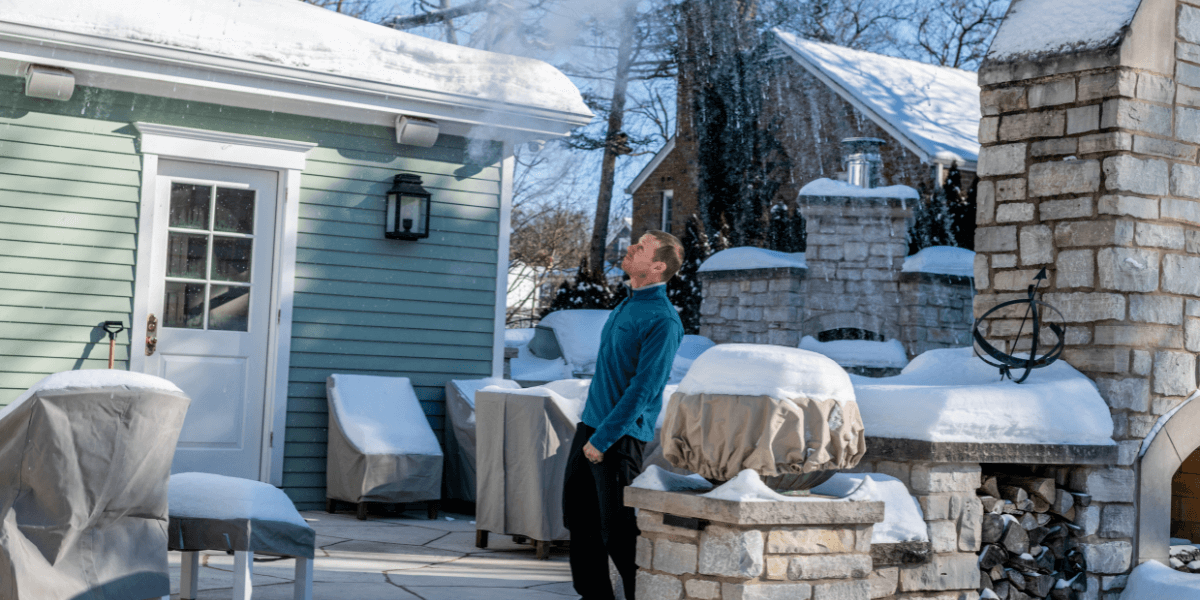 A man standing on his patio, surrounded by a serene snowy landscape.