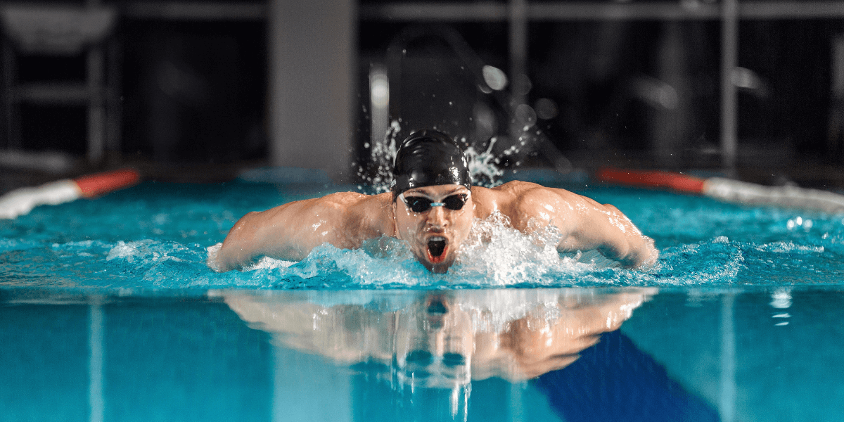 A healthy man swimming in a clear blue pool, showcasing fitness and well-being in a refreshing and active outdoor setting.